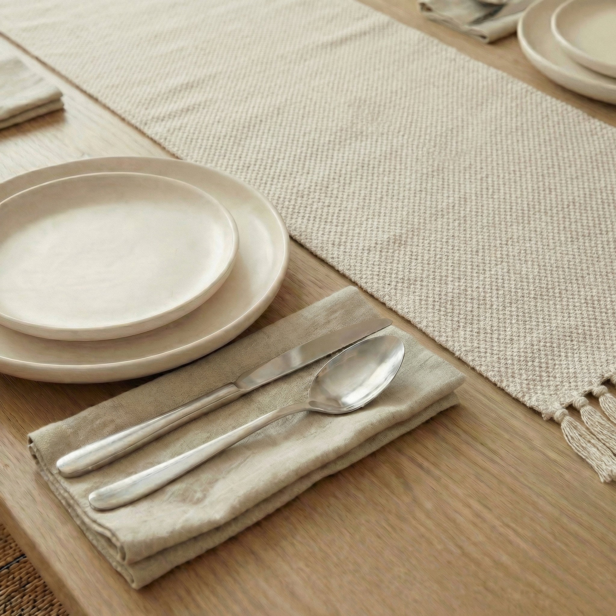 Natural cotton table runner with tassels styled on a wooden dining table