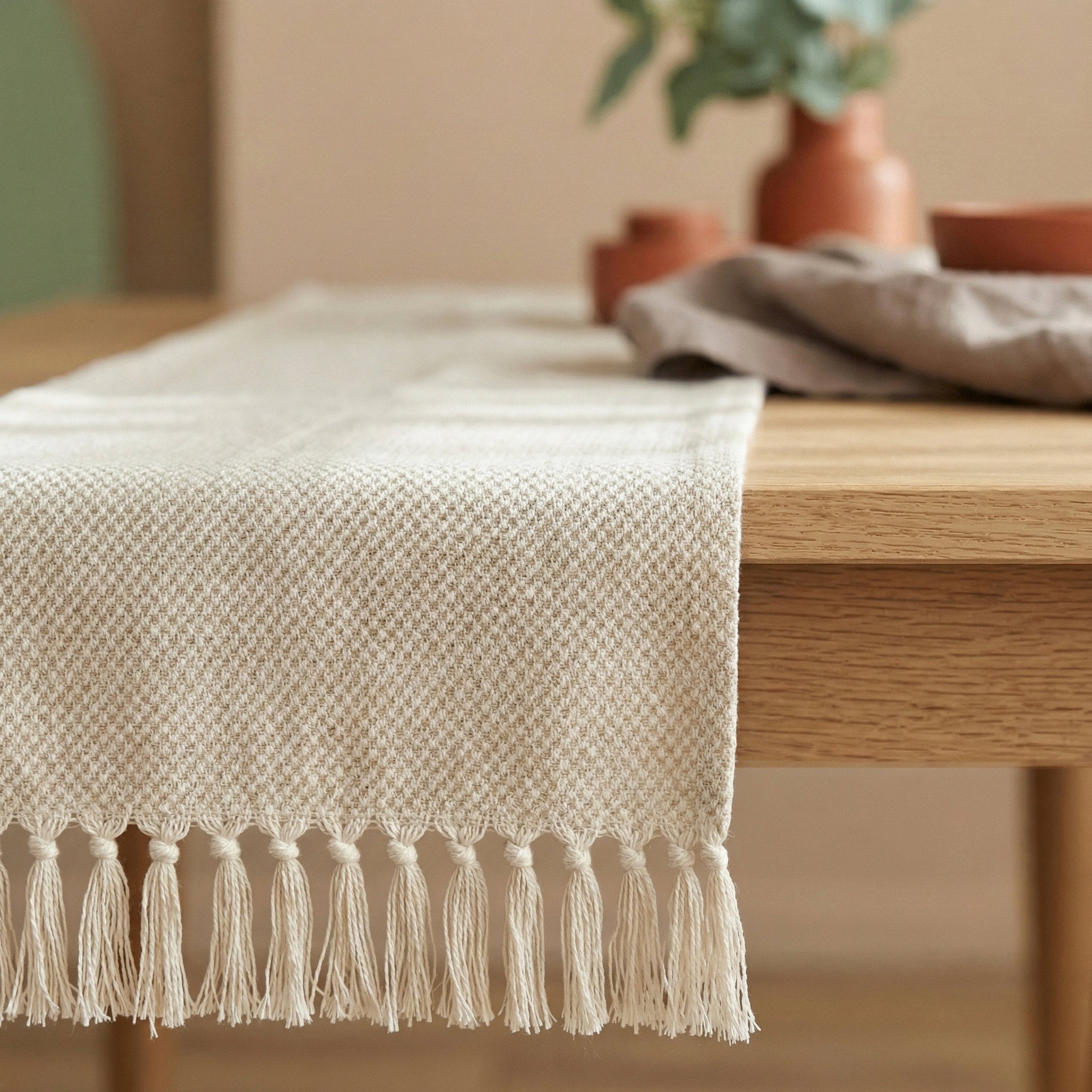Cozy dining room setting featuring a natural cotton table runner with handmade tassels